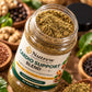 An open jar of Nutrew Cardio Support Blend herbal food supplement, showing the green and brown powder inside, surrounded by ingredients like ginger, garlic, and herbs on a blurred background.