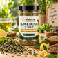 A jar of Nutrew Slim & Detox Tea stands on a wooden table surrounded by loose tea leaves, lemon slices, mint leaves, bowls of herbs, and a glass mug of pale yellow tea. A blurred outdoor green background and a sign reading 'Good Health Brighter Days' appear behind the product.