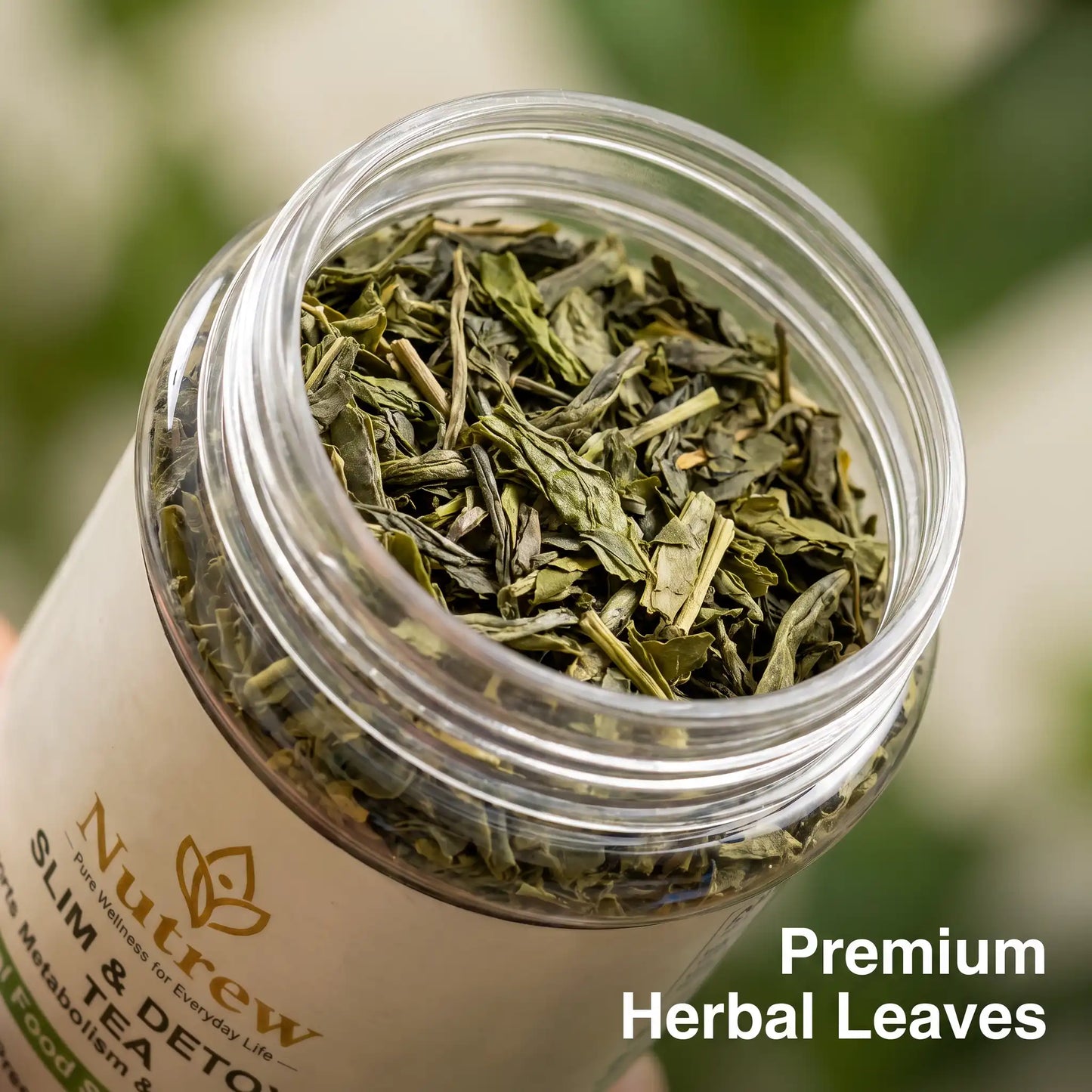 An open clear plastic jar filled with loose green herbal tea leaves, with a cream-colored label reading 'Nutrew Slim & Detox' and text overlay 'Premium Herbal Leaves' on a blurred green background.
