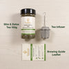 A jar of Nutrey Slim & Detox Tea 150g shown on a light wood background alongside a stainless steel tea infuser and a brewing guide leaflet. Text labels identify the items.